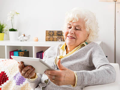 Senior lady looks at an iPad in her livingroom